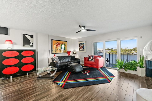 living room featuring a water view, wood tiled floor, a textured ceiling, and a ceiling fan