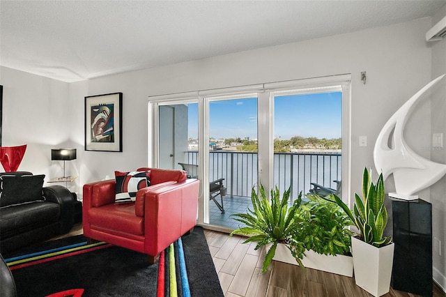 living room with a water view, a textured ceiling, and wood finished floors