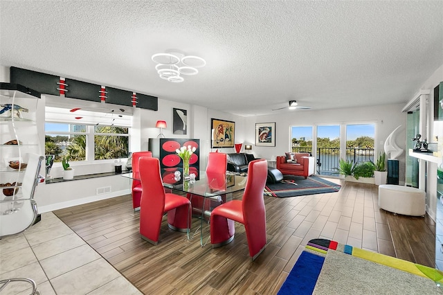 dining space featuring visible vents, ceiling fan, a textured ceiling, and wood finished floors