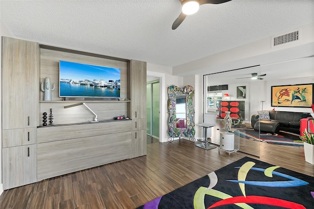 living area featuring a ceiling fan, a textured ceiling, visible vents, and dark wood-style flooring