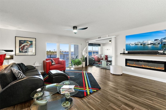 living area with a glass covered fireplace, a textured ceiling, and wood finished floors