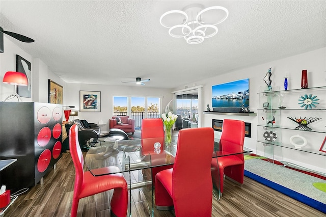 dining area with a textured ceiling, ceiling fan with notable chandelier, and wood finished floors