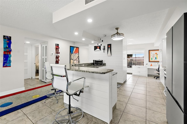 kitchen with light tile patterned floors, visible vents, freestanding refrigerator, a textured ceiling, and recessed lighting