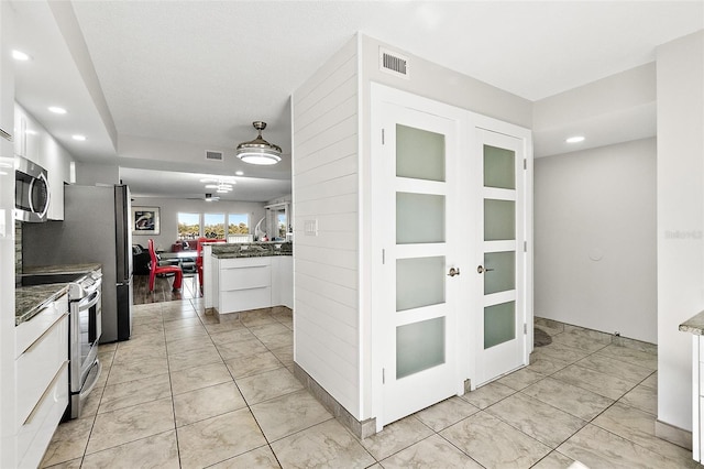 kitchen with visible vents, stainless steel appliances, open floor plan, and white cabinetry