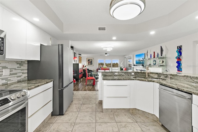 kitchen with visible vents, a raised ceiling, appliances with stainless steel finishes, white cabinetry, and a sink