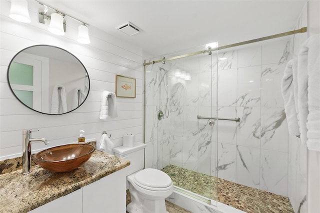 full bath featuring toilet, vanity, a marble finish shower, and visible vents