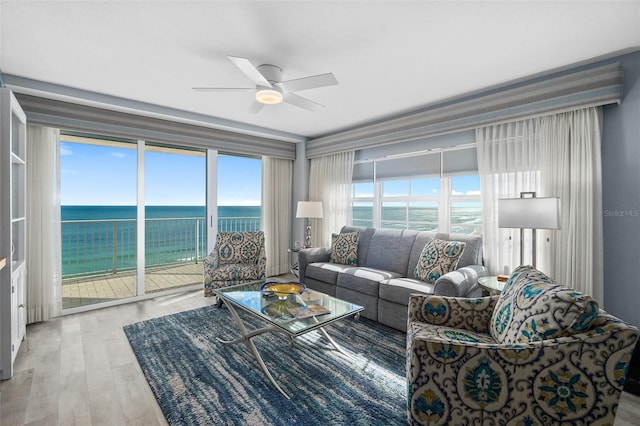 living room featuring ceiling fan, a water view, and wood finished floors