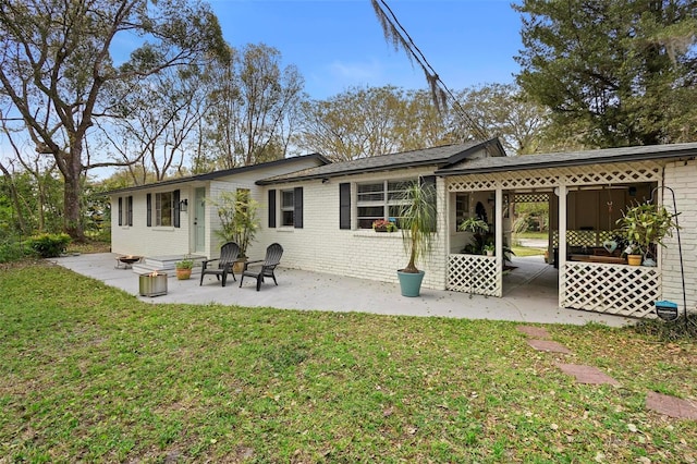 back of house with a patio area, a lawn, and brick siding