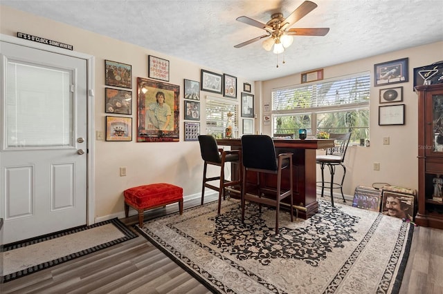 dining area featuring a textured ceiling, ceiling fan, wood finished floors, and baseboards