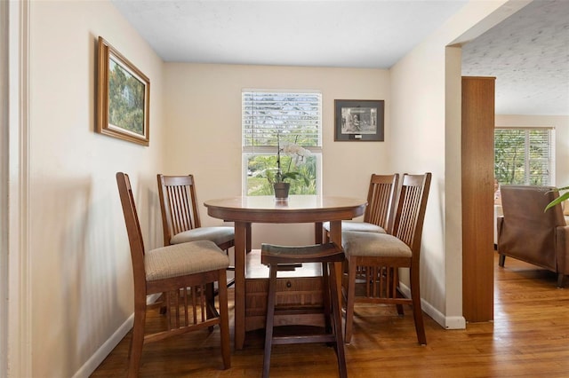 dining space with baseboards and wood finished floors