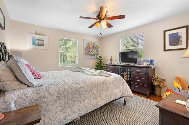 bedroom featuring a ceiling fan, multiple windows, and wood finished floors