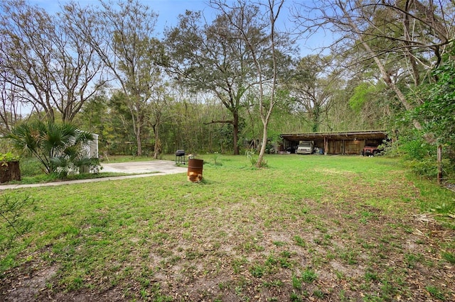 view of yard with a carport, an outbuilding, and a patio area