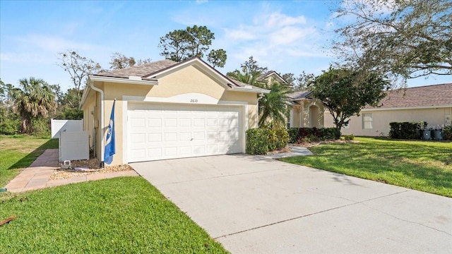 ranch-style home featuring stucco siding, driveway, an attached garage, and a front lawn