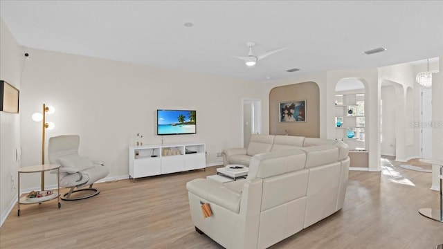 living area featuring a ceiling fan, visible vents, light wood-style floors, and arched walkways