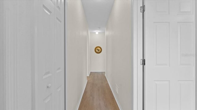 corridor with baseboards and light wood finished floors