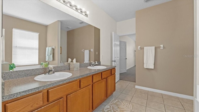 full bath with tile patterned floors, double vanity, baseboards, and a sink