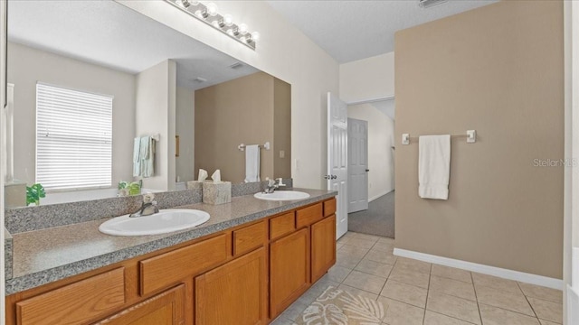 bathroom featuring a sink, baseboards, double vanity, and tile patterned floors