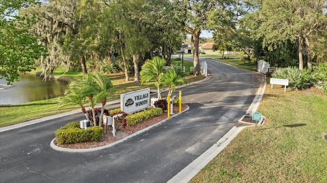 view of street with curbs, a water view, and a gated entry