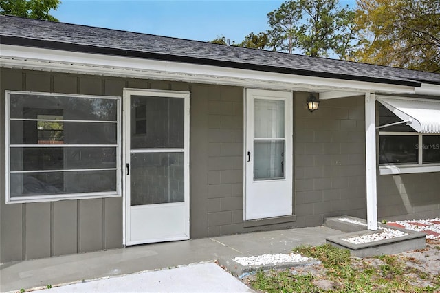 doorway to property with a shingled roof and board and batten siding