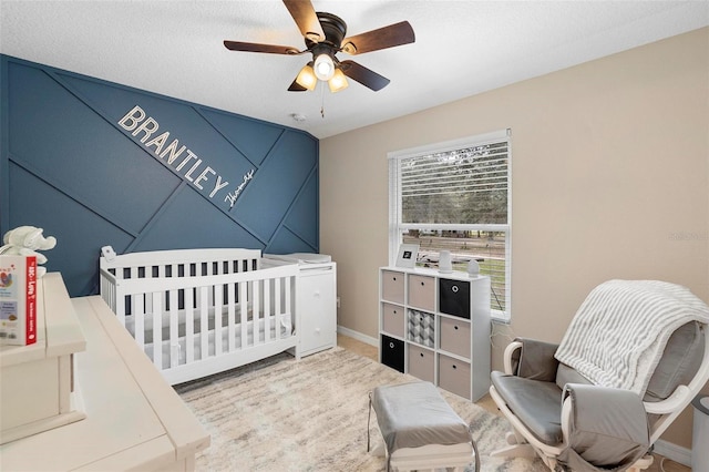 bedroom with a ceiling fan, a nursery area, and baseboards