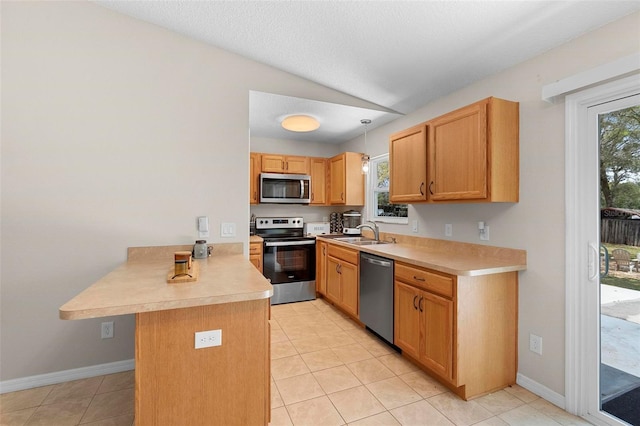 kitchen with stainless steel appliances, lofted ceiling, light countertops, a sink, and a peninsula