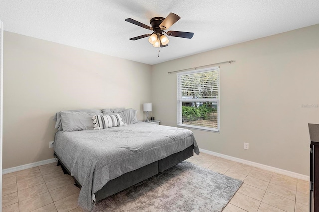 bedroom featuring a textured ceiling, ceiling fan, light tile patterned flooring, and baseboards