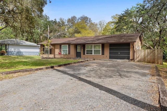 single story home with a garage, a front yard, fence, and aphalt driveway