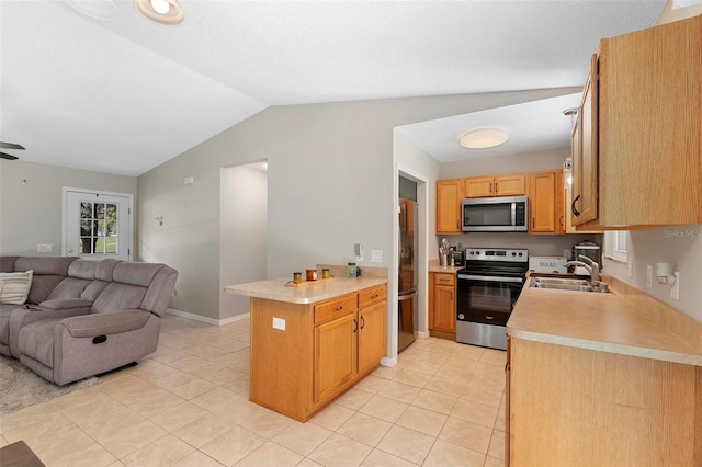 kitchen with lofted ceiling, appliances with stainless steel finishes, open floor plan, light countertops, and a sink