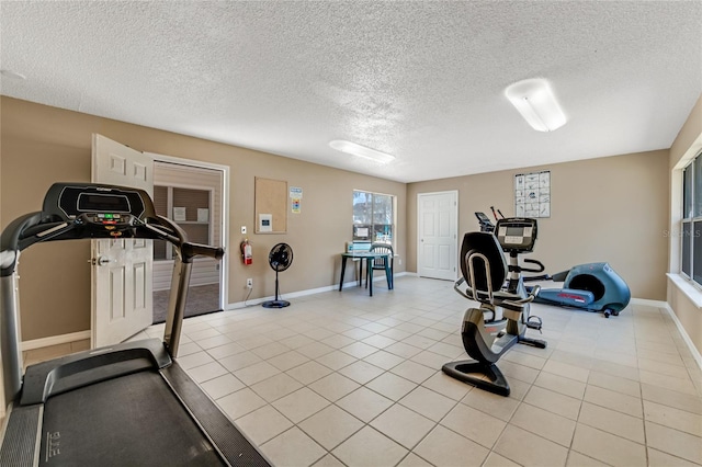 workout area featuring a textured ceiling, baseboards, and light tile patterned floors