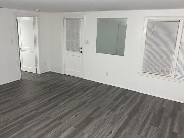 unfurnished room with dark wood-style floors and baseboards