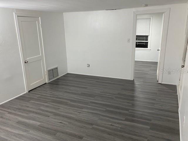 unfurnished room featuring dark wood-style floors and visible vents