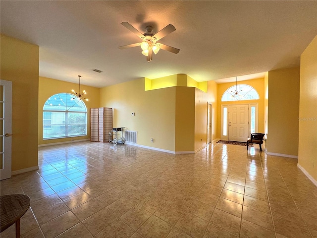 interior space featuring ceiling fan with notable chandelier, tile patterned floors, visible vents, and baseboards