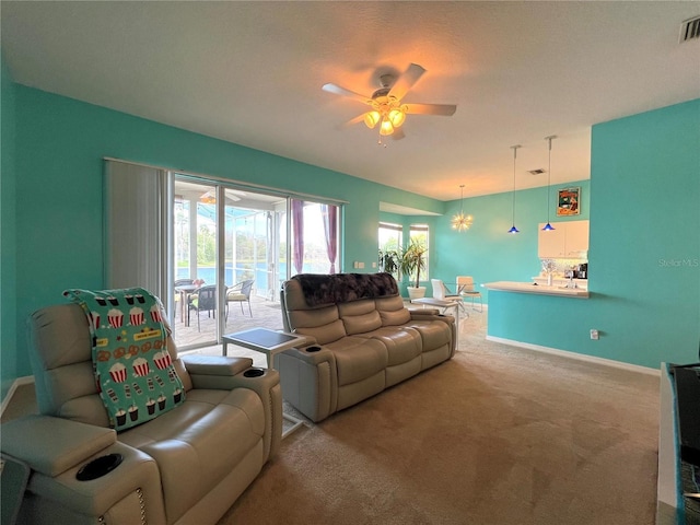 living room with carpet, visible vents, baseboards, and ceiling fan with notable chandelier