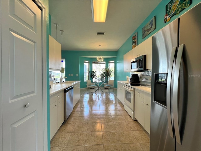 kitchen featuring light countertops, appliances with stainless steel finishes, white cabinetry, and decorative backsplash