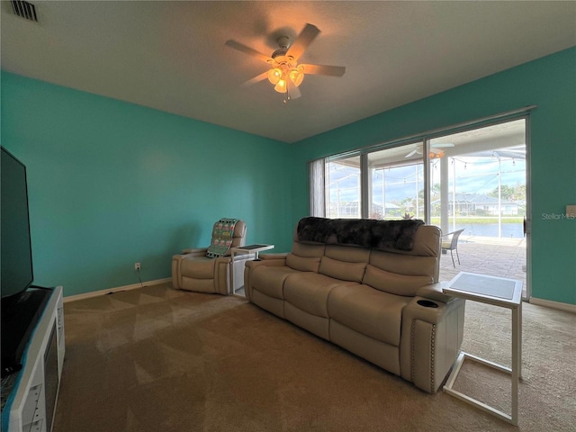 living room featuring carpet floors, visible vents, baseboards, and a ceiling fan