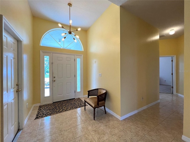 entryway featuring baseboards, light tile patterned flooring, a towering ceiling, and a healthy amount of sunlight