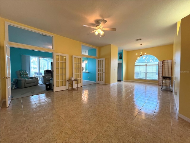 unfurnished living room with visible vents, french doors, ceiling fan with notable chandelier, and a wealth of natural light