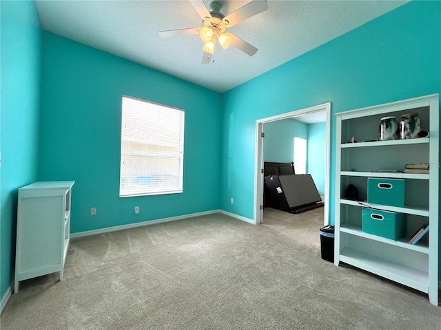 unfurnished bedroom featuring a ceiling fan, carpet, a textured ceiling, and baseboards