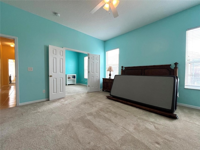 bedroom featuring a textured ceiling, carpet floors, multiple windows, and a ceiling fan