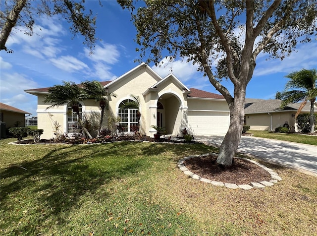 single story home featuring a front yard, driveway, an attached garage, and stucco siding