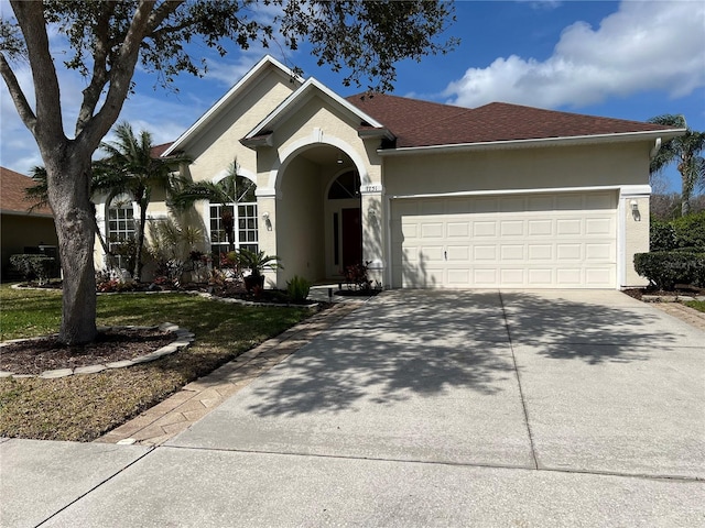 ranch-style house with concrete driveway, roof with shingles, an attached garage, and stucco siding