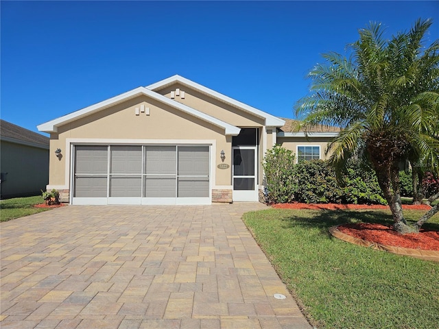 single story home with decorative driveway, stucco siding, an attached garage, stone siding, and a front lawn