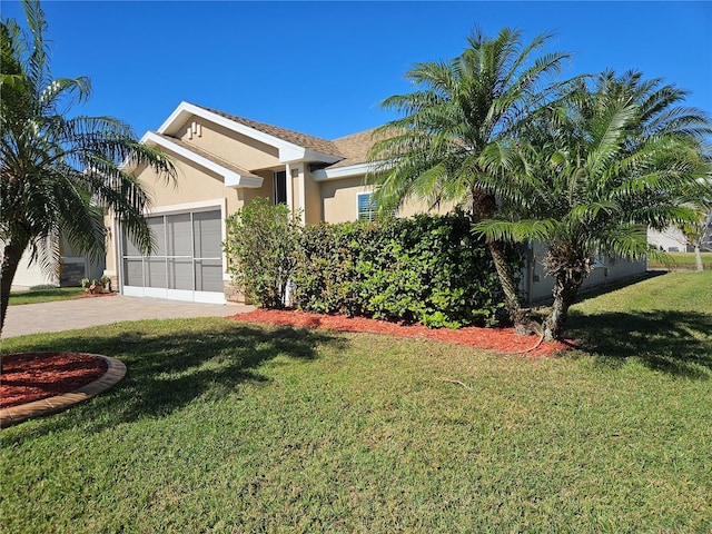 view of front of home with an attached garage, a front lawn, decorative driveway, and stucco siding