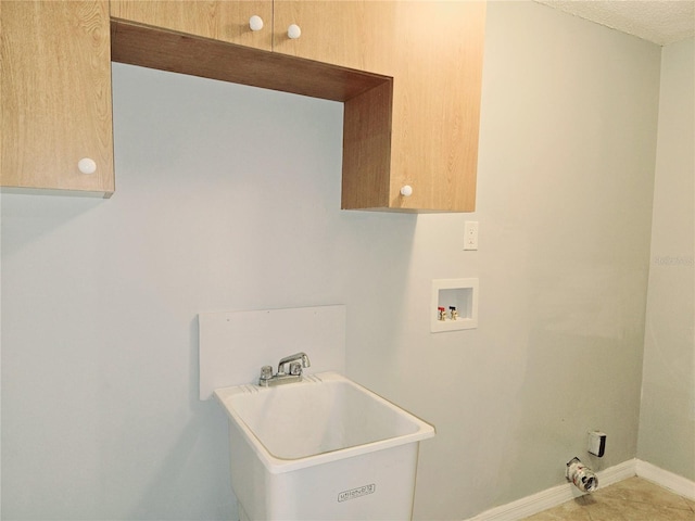 clothes washing area featuring cabinet space, hookup for a washing machine, baseboards, and a sink