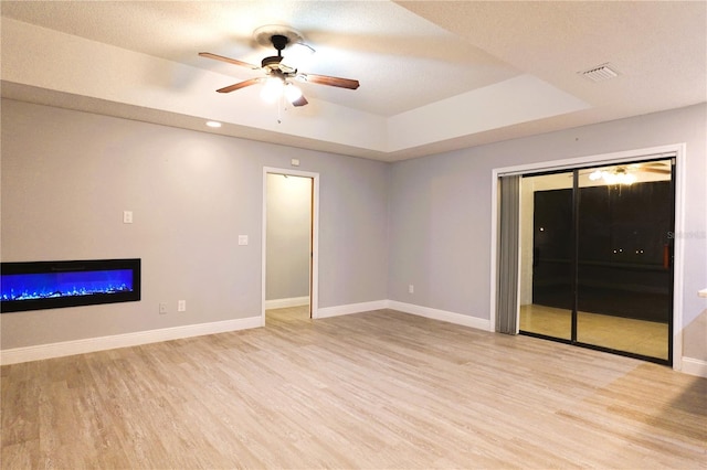 interior space featuring a raised ceiling, baseboards, and light wood finished floors