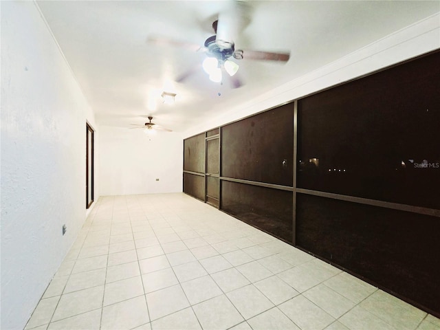 tiled spare room featuring ceiling fan and a textured wall