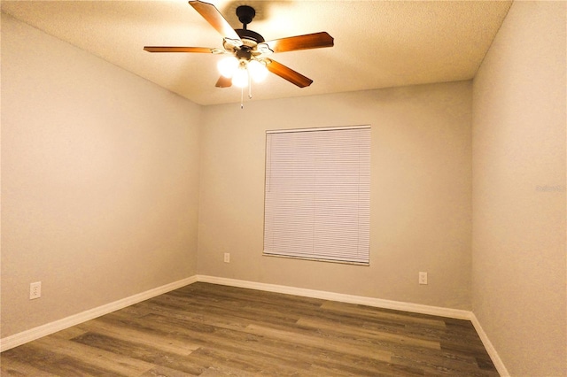 spare room with a textured ceiling, dark wood finished floors, a ceiling fan, and baseboards