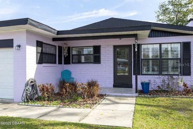 doorway to property featuring brick siding, board and batten siding, and an attached garage