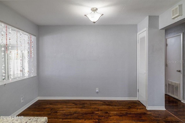 unfurnished room featuring baseboards, visible vents, and wood finished floors