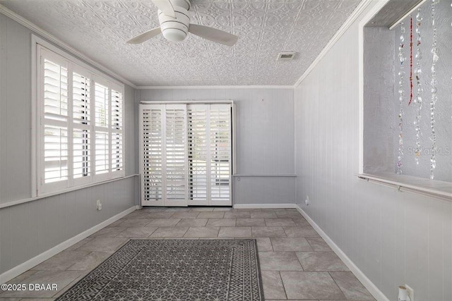 empty room featuring ornamental molding, visible vents, ceiling fan, and baseboards